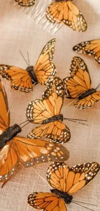 This live wallpaper for phones boasts a beautiful visual art of a group of orange butterflies nestled on top of a vintage-inspired table