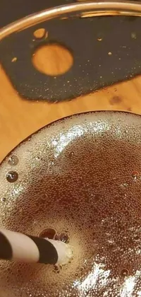This stunning live wallpaper features a highly detailed close-up of a drink in a straw glass with intricate stippled art, surrounded by a brown resin background