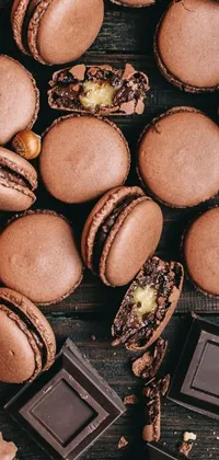 This phone live wallpaper portrays a beautiful pile of chocolate macarons on a natural wooden table