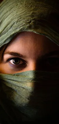 This phone live wallpaper showcases a beautiful woman wearing a green scarf over her face, with sultry eyes peering out from behind