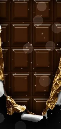 This chocolate live wallpaper features a luscious piece of chocolate sitting on top of a shiny foil