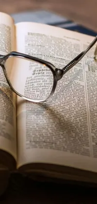 This phone live wallpaper features a stunning image of square-rimmed glasses perched on top of the pages of an open book