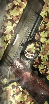 This phone live wallpaper showcases a close-up of a gun on a camouflage surface, complemented by the Tumblr and Shin Hanga art styles