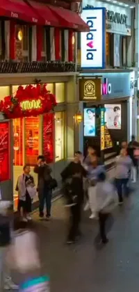 This live wallpaper features a vibrant city scene with people strolling down a busy street under warm street lights