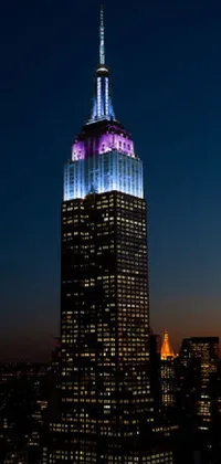 This live wallpaper depicts the Empire State Building, lit up in shades of purple and blue with Renaissance lighting design