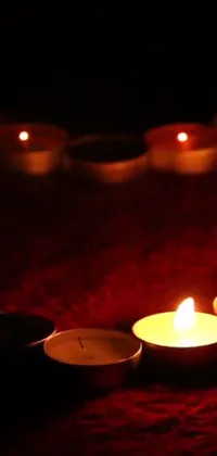 This live wallpaper showcases a group of candles arranged on a red blanket