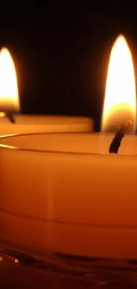 This phone live wallpaper captures the beauty of three lit candles on a wooden table