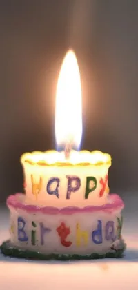 This phone live wallpaper showcases a stunning close-up of a colorful birthday cake with a glowing candle sitting at its center