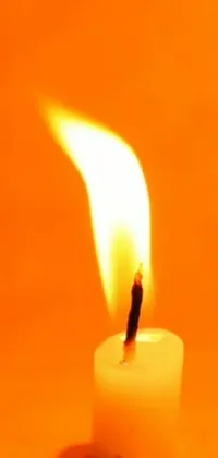 This live wallpaper portrays a tranquil setting of a candle's flickering flame on a table with an orange background that exudes energy