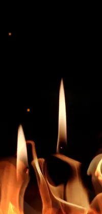 This phone live wallpaper features a close-up of two lit candles in the dark, creating a warm and inviting atmosphere