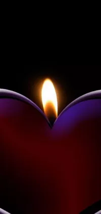This live phone wallpaper shows a heart-shaped candle with a flickering flame in the center, in a profile shot
