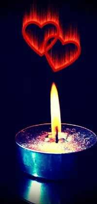 This phone live wallpaper showcases a stunning glowing candle with two heart-shaped objects placed over the flame