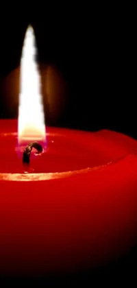 This phone live wallpaper showcases a photorealistic image of a red candle in the dark, creating a warm and intimate ambiance on your phone screen