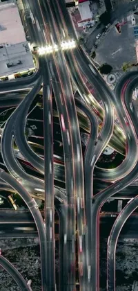 This phone live wallpaper features an aerial view of a highway intersection at night with flowing curves and colorful lights creating a surreal and futuristic look