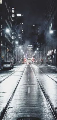 This phone live wallpaper depicts a realistic city street at night, complete with heavy traffic, shadowy buildings, and dazzling lights beaming from street lamps and car headlights