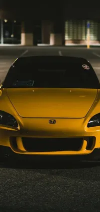 This dynamic live wallpaper features a yellow sports car parked on a city street at night time