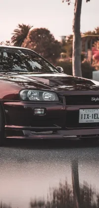 This live phone wallpaper captures a stunning, red Nissan Skyline R34 parked on the roadside
