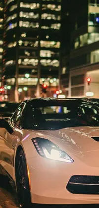 This live wallpaper features a white sports car parked on a city street at night