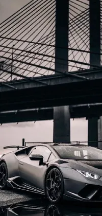 This phone live wallpaper features a silver sports car parked in front of a bridge in New York City