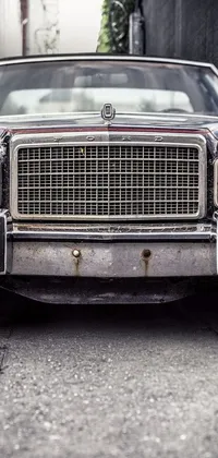 Transform your phone's background with a stunning live wallpaper capturing a vintage car parked on the side of a street