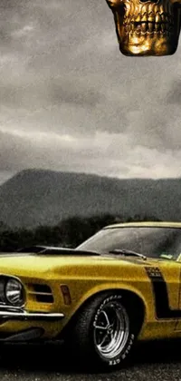 A dynamic phone wallpaper featuring a yellow car with a skull atop amidst picturesque mountain scenery and rain