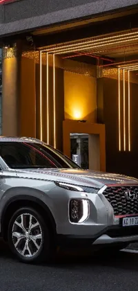 Get this stunning live wallpaper for your phone! Featuring a silver SUV parked in front of a beautifully-detailed building, this scene is perfect for any urban lover