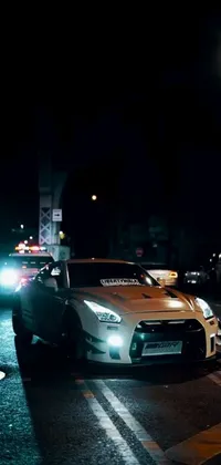 This phone live wallpaper showcases a GTR Xu1 car parked on the street near a race track at night, providing a realistic scene