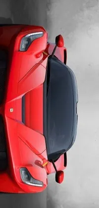 This phone wallpaper depicts a red sports car parked in a modern lot