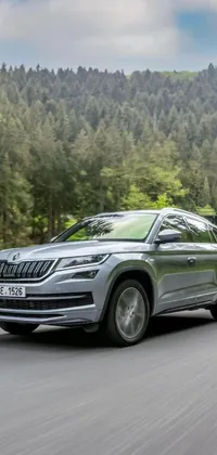 This captivating live wallpaper features a silver SUV driving through a forested road