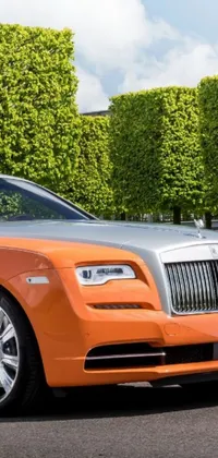 This stunning live wallpaper features an eye-catching orange Rolls Royce Wraith parked on the roadside