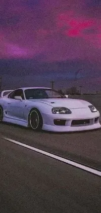 This unique live wallpaper showcases a violet Toyota Supra, parked on the side of a road in a mesmerizing scene