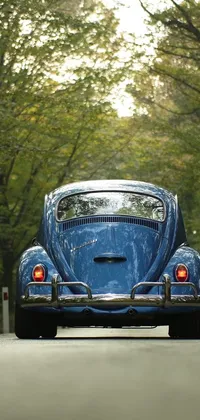 This live wallpaper features a striking photo of a blue beetle-inspired car driving down a road lined with trees