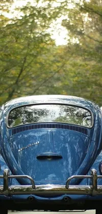 This blue 1959 beetle car live wallpaper boasts photorealistic details of a vintage car cruising along a winding street surrounded by lush trees