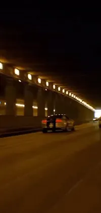 This live wallpaper showcases a car driving through a tunnel at night, showcasing beautiful cityscapes, including a bay bridge and an aqueduct