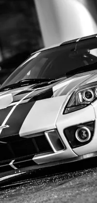 This live mobile wallpaper features a stunning black and white photograph of a sleek sports car captured from the front, showcasing its impressive hood and grille