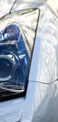 This phone live wallpaper features a stunning photorealistic image of a headlight on a white car