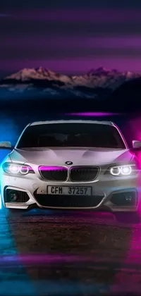 This live phone wallpaper showcases a sleek white BMW parked in front of a majestic mountain, with glowing tubes in the background