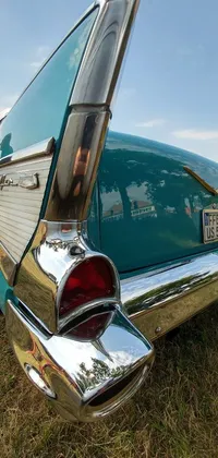 This green car live wallpaper showcases a stunning 1957 Chevrolet Bel Air parked on a grass covered field