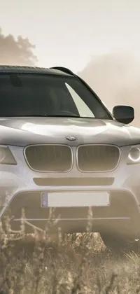 This live wallpaper features a white BMW SUV parked in a serene field, captured beautifully in UHD resolution by Matija Jama, with volumetric fog light and stunning lighting adding to its charm