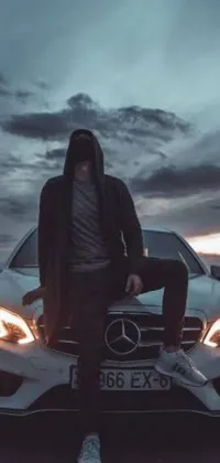 Transform your Android device with a phone live wallpaper that captures a stunning photograph of a man seated on the hood of a Mercedes Benz
