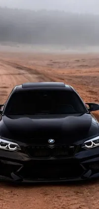 This phone live wallpaper showcases a black BMW car parked on a dirt road, creating a stunning minimalist design with a front profile of the vehicle