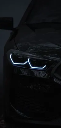 This phone live wallpaper features a close-up of a striking and sleek BMW car in the dark