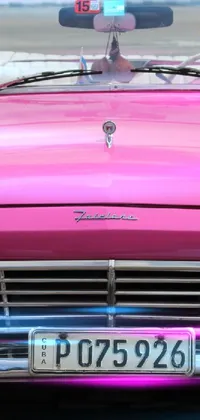 Enjoy a lively and eye-catching live wallpaper on your phone with this pink convertible Ford parked in a colorful lot