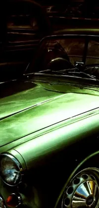 This stunning phone live wallpaper features a vintage green car parked in a spacious lot