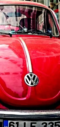 This phone live wallpaper features a stunning close-up frontal shot of a vibrant red VW beetle parked by the side of the road