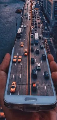 This phone live wallpaper features digital art depicting a modern cell phone held in hand against a backdrop of highways and cityscape