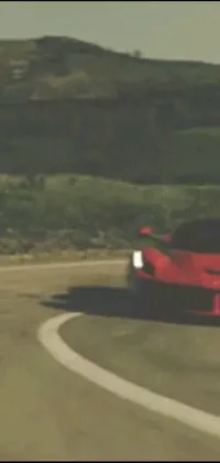 This live wallpaper showcases a red sports car driving down a winding road in a synthetism style