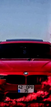 Get revved up with this stunning live wallpaper featuring a fast and furious red BMW sports car emitting smoke