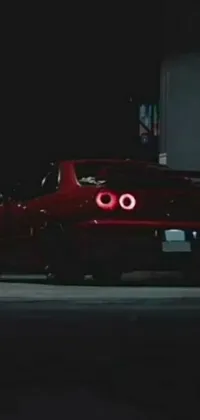 This live wallpaper showcases a stunning red sports car driving through a city street at night, surrounded by bright neon lights