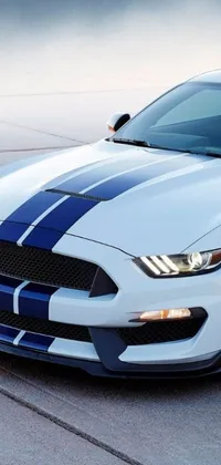 Rev up your phone's home screen with this phone live wallpaper featuring a white and blue mustang parked in a lot
